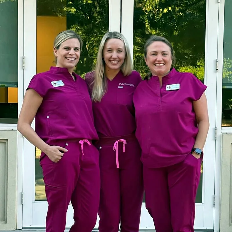 Three Highland Park Animal Hospital team members in scrubs outside the hospital entrance